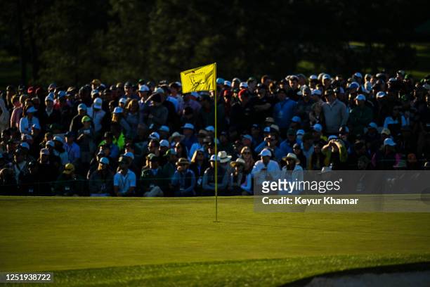 View of the pinflag as patrons gather around the 18th hole green during the final round of the 2023 Masters Tournament at Augusta National Golf Club...