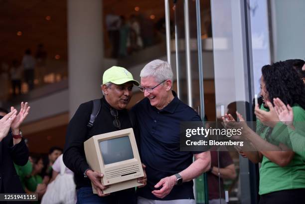 Tim Cook, chief executive officer of Apple Inc., right, reacts to a customer carrying a Macintosh SE during the opening of the new Apple BKC store in...