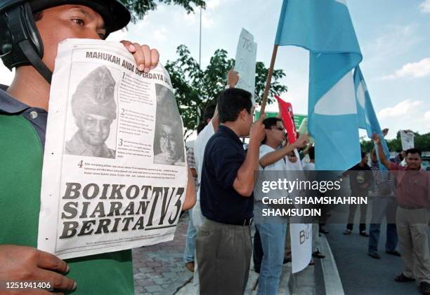 Man holds a newspaper cutting with the headlines "Boycott TV3 News" during a demonstration in front of the headquarters of Malaysia's TV3 television...