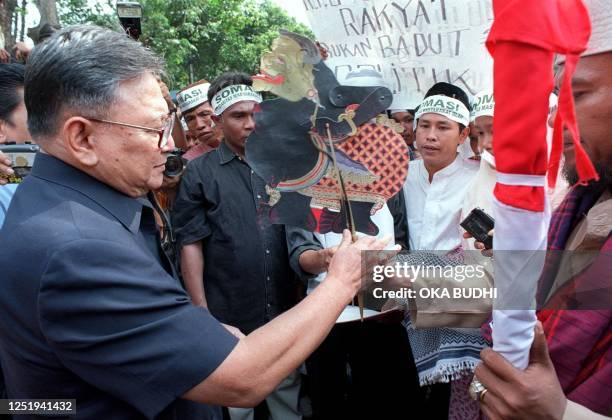 The head of the Elections Committee Rudini receives a traditional Java puppet called "Semar" and a sword covered by an Indonesia flag from protesters...