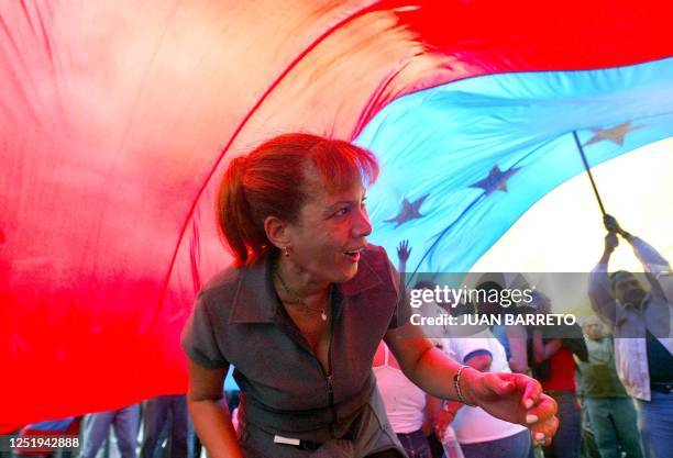 Opposer to Venezuelan President Hugo Chavez passes under a giant flag during a protest demanding Chavez's resignation 15 June in Caracas. The...