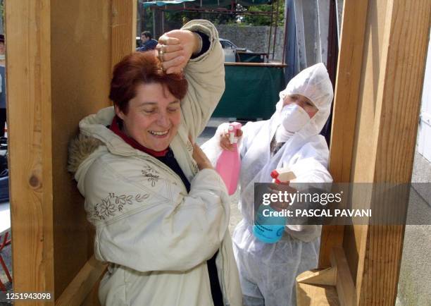 Une femme se fait symboliquement pulvériser de produits désinfectants dans un faux pédiluve, le 05 mai 2002 à Villemagne, après avoir voté pour le...