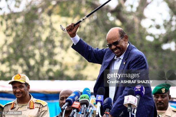 Sudanese President Omar al-Bashir waves a walking stick as he gives a speech in Nyala, the capital of South Darfur province on September 21 while...