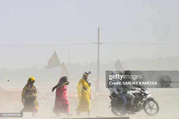 People walk through a dust storm on a hot summer day in Prayagraj on April 18, 2023.