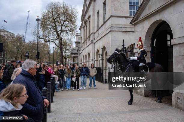 Tourists gather around a mounted cavalry trooper of The King's Life Guard at Horse Guards on April 18, 2023 in London, England. The Coronation of...