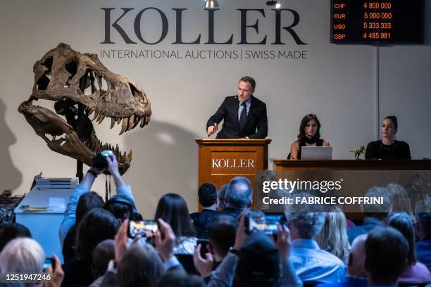 Koller auction house director Cyril Koller gestures next to the skull of the 'Trinity' during sale of the skeleton of the Tyrannosaurus-Rex by Koller...