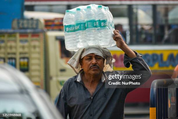 Man is seen carrying stacks of packaged water during afternoon heat in Kolkata , India , on 18 April 2023 . Temperature sore well above 40 Celsius as...