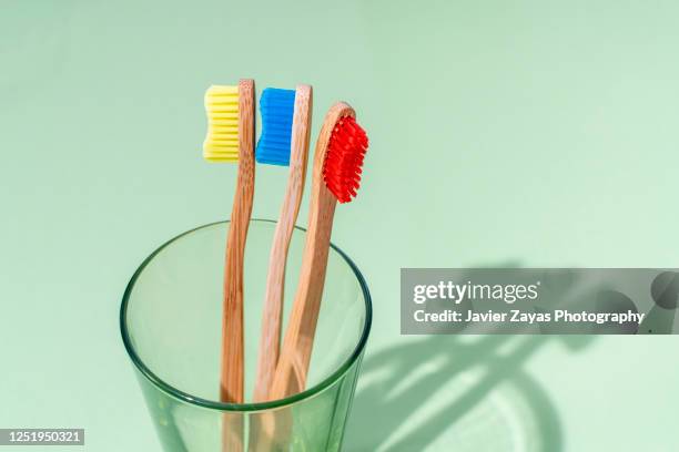 three bamboo toothbrushes in a glass on a green background - three objects stock pictures, royalty-free photos & images