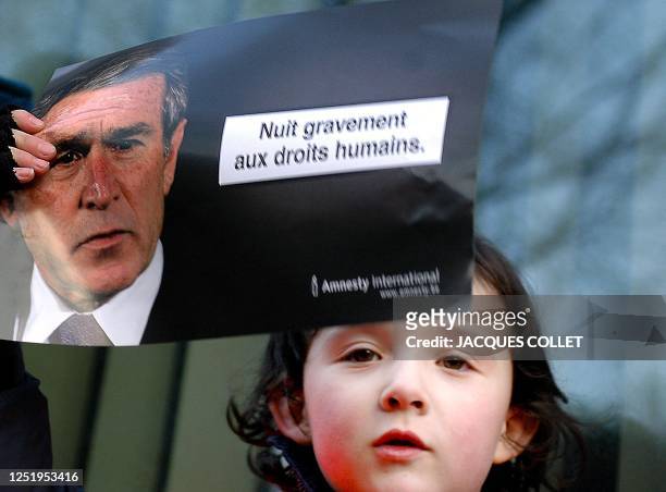Girl holds a poster showing US President George W. Bush and reading "Seriously damages human rights" during an anti-Bush demonstration in front of...