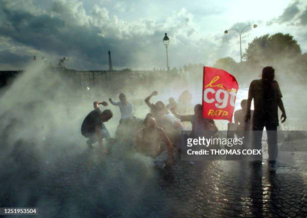 Des manifestants tentent de se protéger des gaz lacrimogènes et des bombes à eau, lors des incidents survenus, le 10 juin 2003 aux abords de la place...