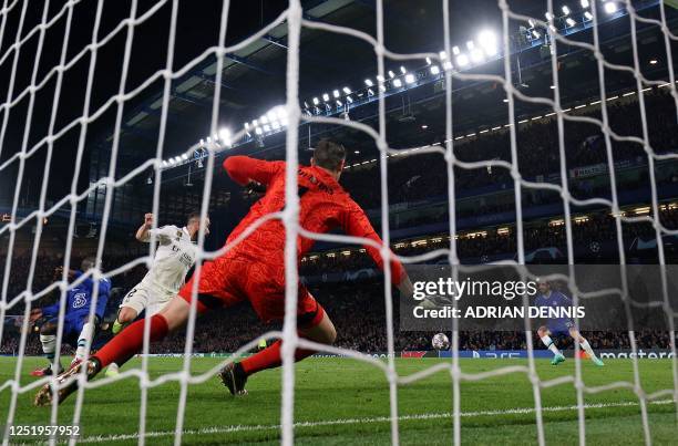 Real Madrid's Belgian goalkeeper Thibaut Courtois (C0 dives to save a shot by Chelsea's Spanish defender Marc Cucurella during the Champions League...
