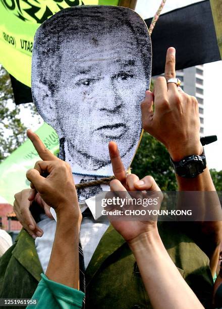 Protesters make a dirty sign in front of the effigy of US President George W. Bush during a protest near the US embassy in Jakarta, 28 March 2003....