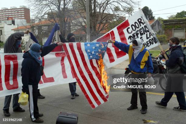 Manifestantes queman frente a la residencia presidencial en Montevideo una bandera de Estados Unidos en protesta contra un posible Tratado de Libre...