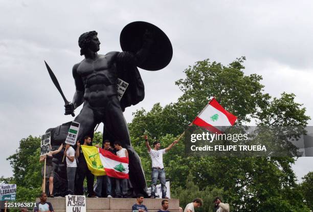 Demonstrators on a giant sculpture in Hyde Park hold lebanese and Hezbollah flags as they takes part in a march through central London 22 July 2006...