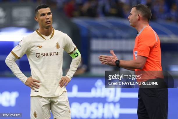 Nassr's Portuguese forward Cristiano Ronaldo listens to the English referee Michael Oliver during the Saudi Pro League football match between...
