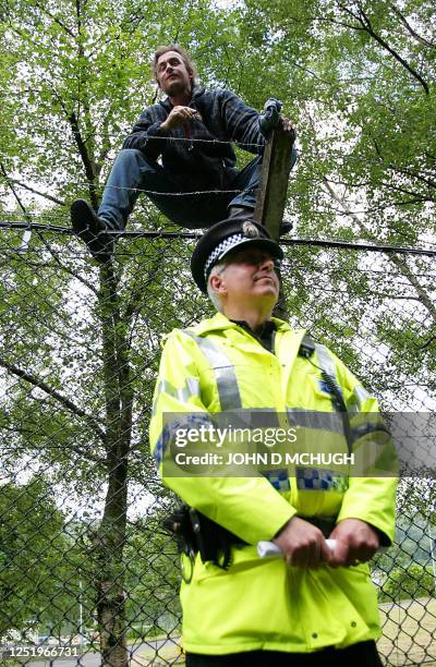 Man sits atop the perimeter fence of Faslane Naval Base in Scotland, 4 July 2005, as part of a non-violent blockage by activists. Thousands of...