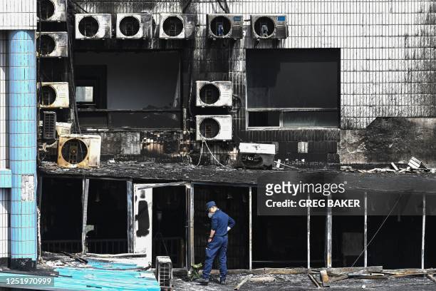 An investigator inspects the damage at the Changfeng Hospital in Beijing on April 19 after a fire broke out a day earlier. - An investigation was...