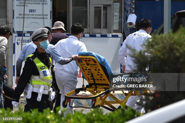 Workers bring a gurney into the Changfeng Hospital in Beijing on April 19 after a fire broke out a day earlier. - An investigation was underway on...