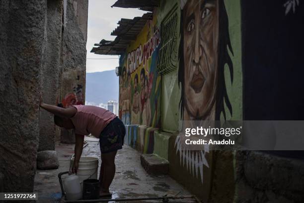 Woman supplies water next to a mural, in the San Agustin neighborhood, in Caracas, on April 8, 2023. Dozens of artists beautify the San Agustin...