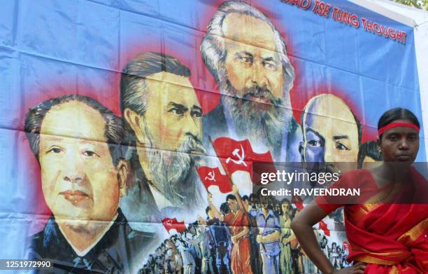 Activists from the Communist Party of India -Marxist-Leninist stand in front of a poster of International Communist Party leaders as they listen to a...