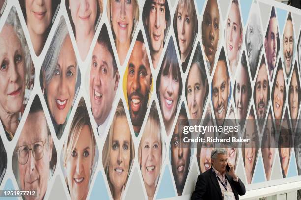 The faces of Harper Collins authors look down on a delegate at the publisher's stand during the first day of the London Book Fair at Hammersmith's...