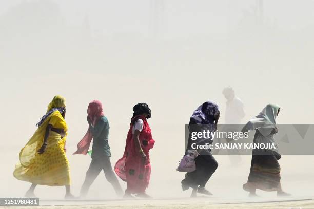 People walk through a dust storm on a hot summer day in Prayagraj on April 18, 2023.