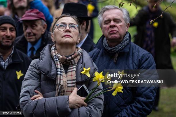 Woman holds yellow daffodils as she attends a public viewing during ceremonies marking the 80th anniversary of the start of the Warsaw Jewish Ghetto...