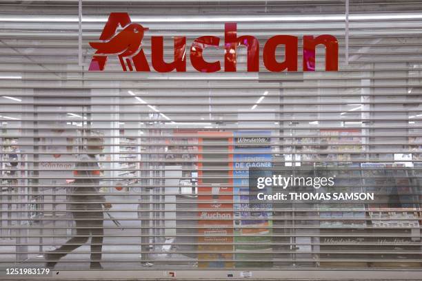 Man walks behind the closed metal shutter of an Auchan supermarket as French General Confederation of Labour trade union members occupy the store to...