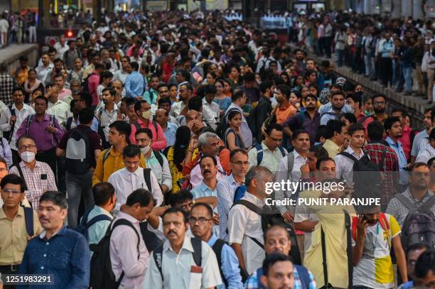 People crowd on platforms as they wait for their train at the Chhatrapati Shivaji Terminus railway station Mumbai on April 19, 2023. - India is set...