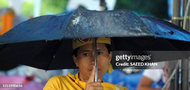 An anti-government protestor sits in the rain while waiting a court decision in Prime Minister Samak Sundaravej's cooking show case inside the...