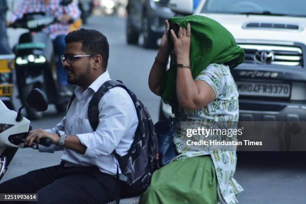 Woman riding pillion covers her head and face with a dupatta in the sweltering afternoon heat as mercury rises higher in the city, in Thane, on April...