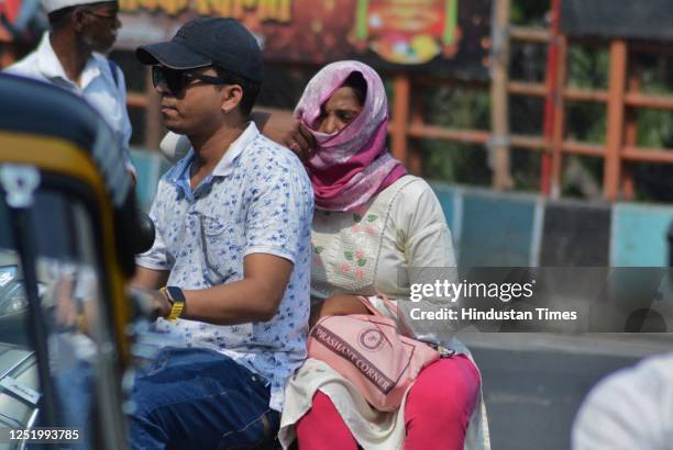 Woman riding pillion covers her head and face with a dupatta in the sweltering afternoon heat as mercury rises higher in the city, in Thane, on April...