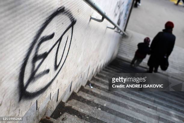 Pedestrians walk past an anti EU graffiti in downtown Belgrade on December 8, 2011. Serbia is holding its breath to see if the European Union on...