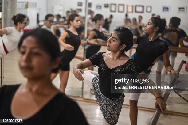 Ballet students rehearse at a gym in Lima on April 11, 2023. - At an arid and dry hill in Lima, a group of girls wearing leotards stand on their toes...