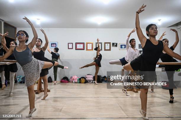 Ballet students rehearse at a gym in Lima on April 11, 2023. - At an arid and dry hill in Lima, a group of girls wearing leotards stand on their toes...