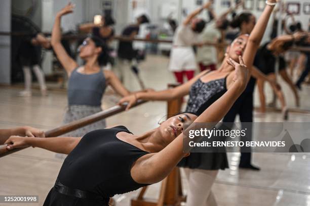 Ballet students rehearse at a gym in Lima on April 11, 2023. - At an arid and dry hill in Lima, a group of girls wearing leotards stand on their toes...