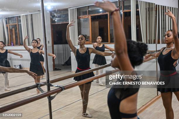 Ballet students rehearse at a gym in Lima on April 11, 2023. - At an arid and dry hill in Lima, a group of girls wearing leotards stand on their toes...