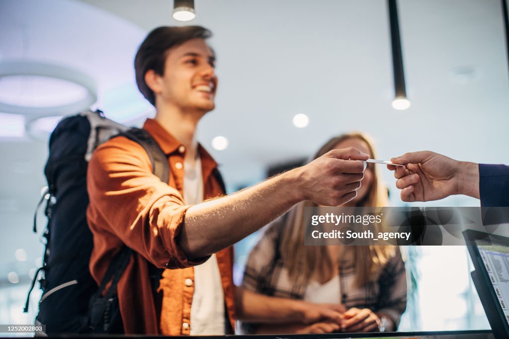 Couple travelers on hotel reception talking to male receptionist