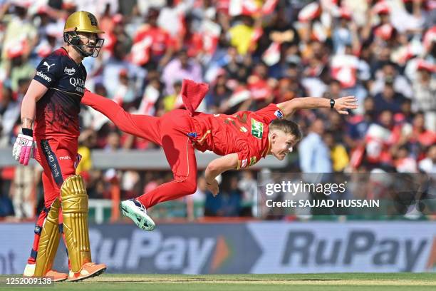 Punjab Kings' Nathan Ellis bowls past Royal Challengers Bangalore's Faf du Plessis during the Indian Premier League Twenty20 cricket match between...