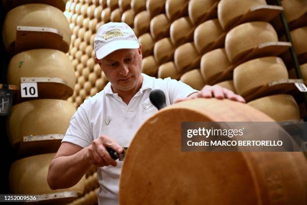 Worker cuts a wheel of Parmigiano Reggiano cheese at the Casearia Castelli, member of Lactalis Group, at the Caseificio Tricolore in Reggio Emilia,...