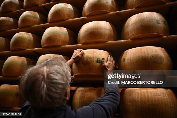 Worker turns a wheel of Parmigiano Reggiano cheese in the ripening department of the Casearia Castelli, member of Lactalis Group, at the Caseificio...