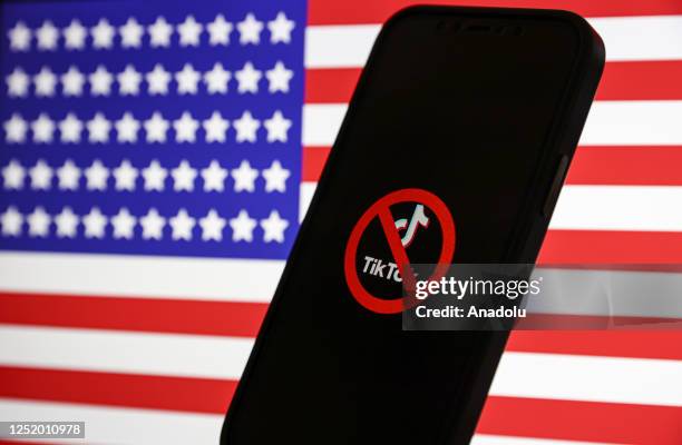 In this photo illustration, logo of Tiktok is displayed on mobile phone screen in front of flag of United States, in Ankara, Turkiye on April 20,...