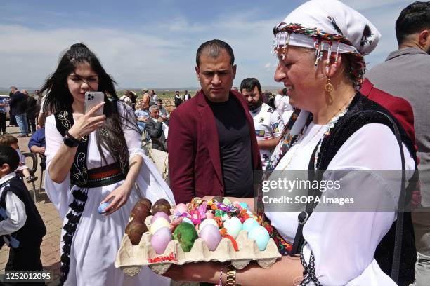 Yazidi woman is seen handing out painted eggs to guests during the Red Wednesday celebration in Bacinê village. Yazidi Kurds living in the Bacine...