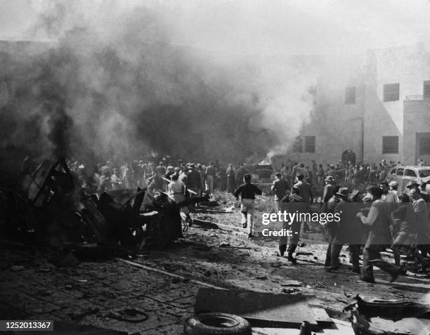 People run around the building which housed Jewish governmental council offices after a car bomb exploded on March 11 in Jerusalem, during the 1948...