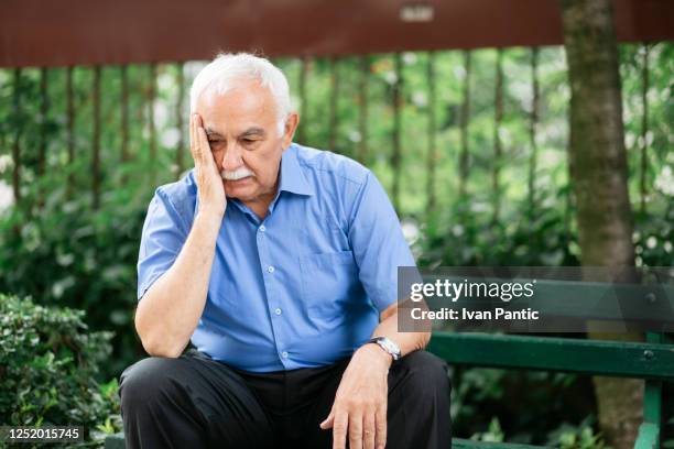 portrait of an anxious elderly man sitting in the park - lost stock pictures, royalty-free photos & images