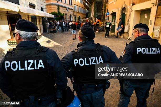 Police officers stand by as Feyenoord fans drink beer and cheer outside a pub in central Rome, prior to the UEFA Europa League quarter-finals second...