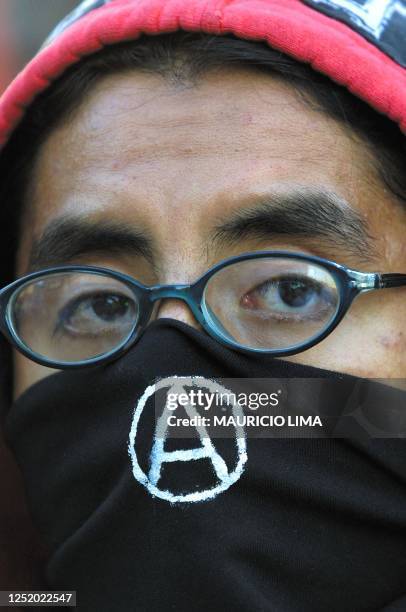 An anarchist protester covers his face with a black bandana during a demonstration 20 March in Monterrey commemorating the death of Carlo Giulani, an...