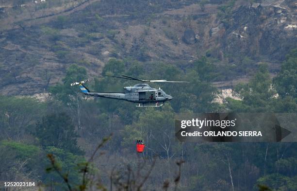 Honduran Air Force helicopter loads water from Los Laureles dam to fight forest fires in the mountains surrounding Tegucigalpa, on April 20, 2023. -...