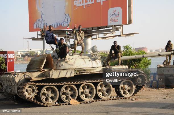 Sudanese army soldiers, loyal to army chief Abdel Fattah al-Burhan, sit atop a tank in the Red Sea city of Port Sudan, on April 20, 2023. More than...