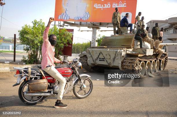 Man raises his arm in support as he drives near Sudanese army soldiers loyal to army chief Abdel Fattah al-Burhan, manning a position in the Red Sea...